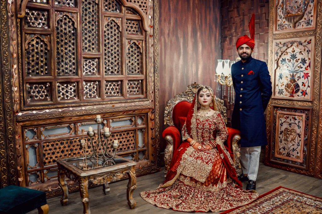 Pre-wedding shoot couple in traditional royal attire with elegant backdrop